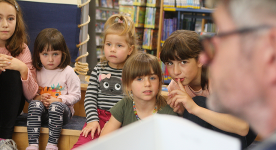 Kinder im Lesezelt der Bibliothek die einem Vorleser lauschen