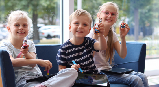 Drei Kinder halten Edurino Figuren in die Luft