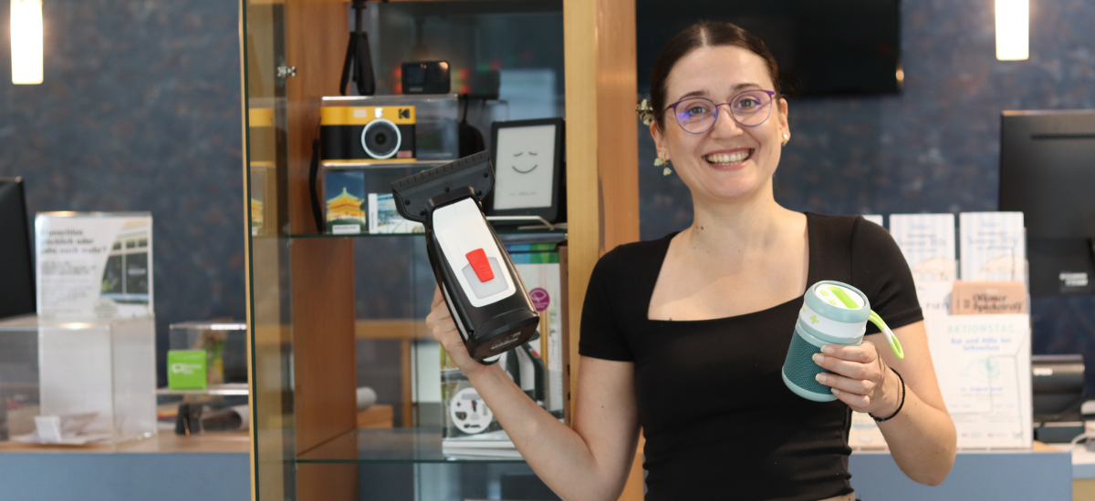 Maja Kos präsentiert die Bibliothek der Dinge der Brigitte-Reimann-Stadtbibliothek Hoyerswerda. In den Händen hält sie einen Fenstersauger und eine Galakto-Box.